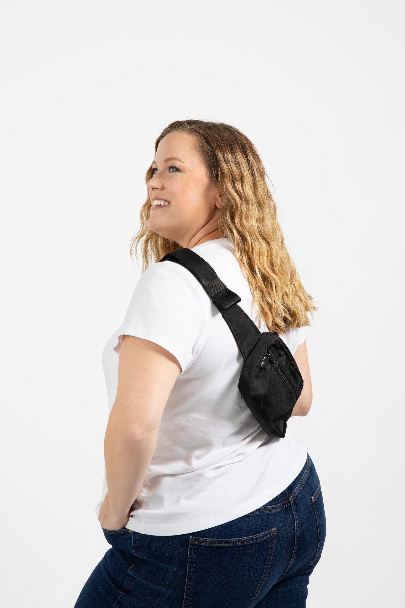 Woman wearing a black plus size crossbody bag on a white background